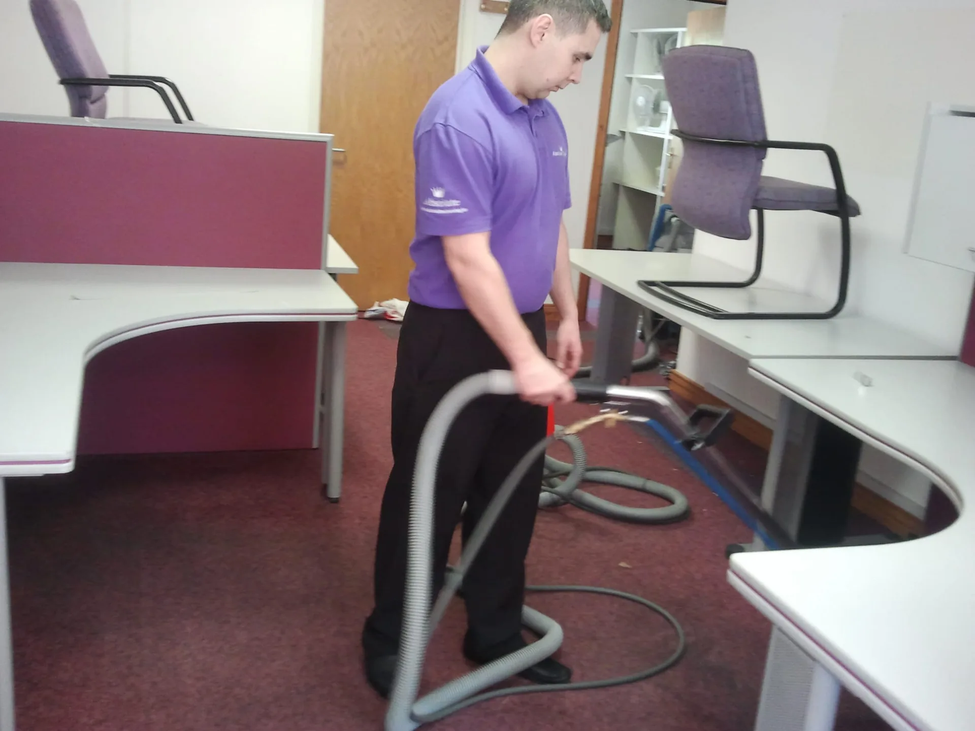 Worker cleaning office carpet with professional extraction equipment