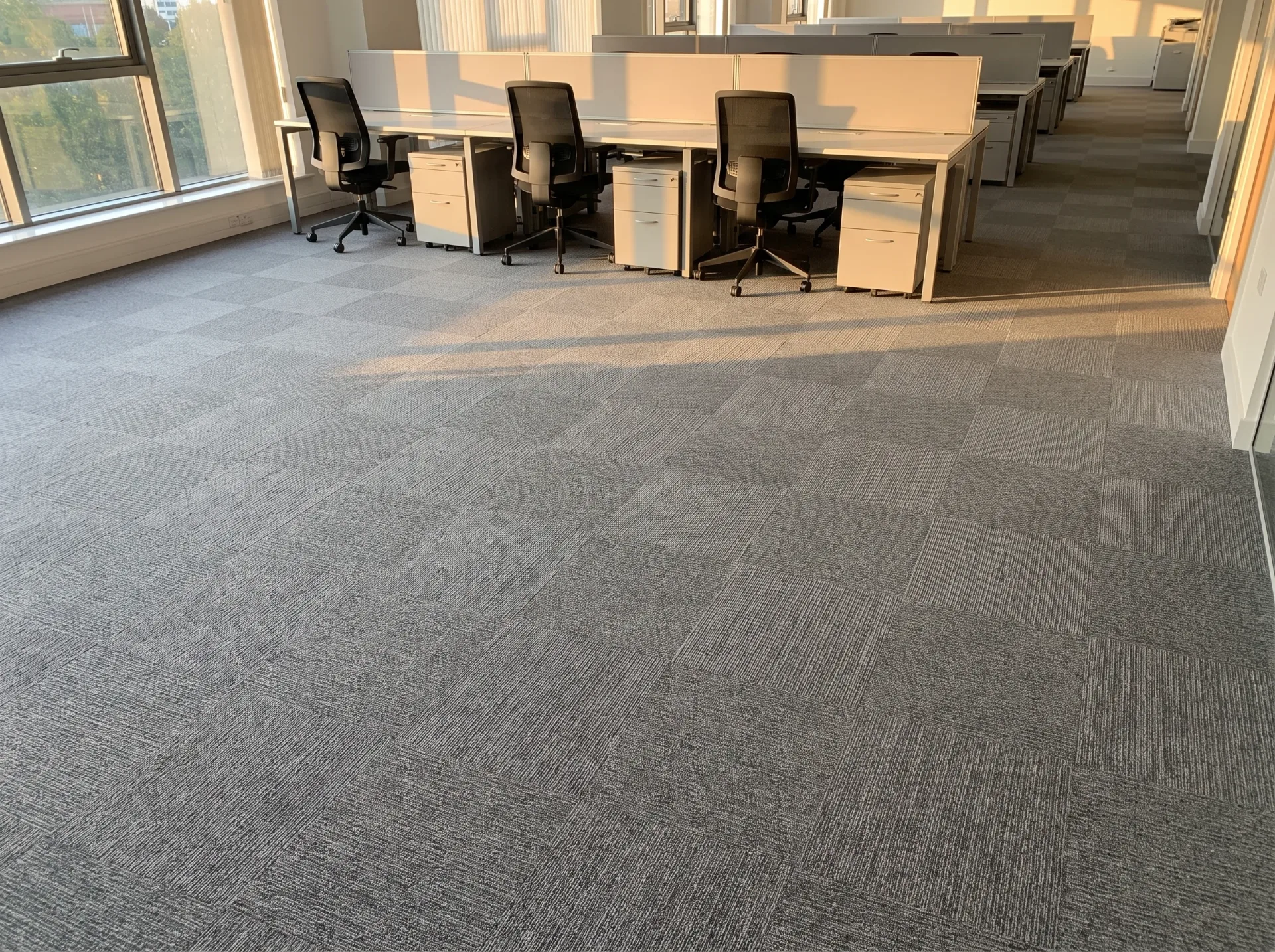 Clean gray office carpet in modern commercial workspace with desks and black chairs