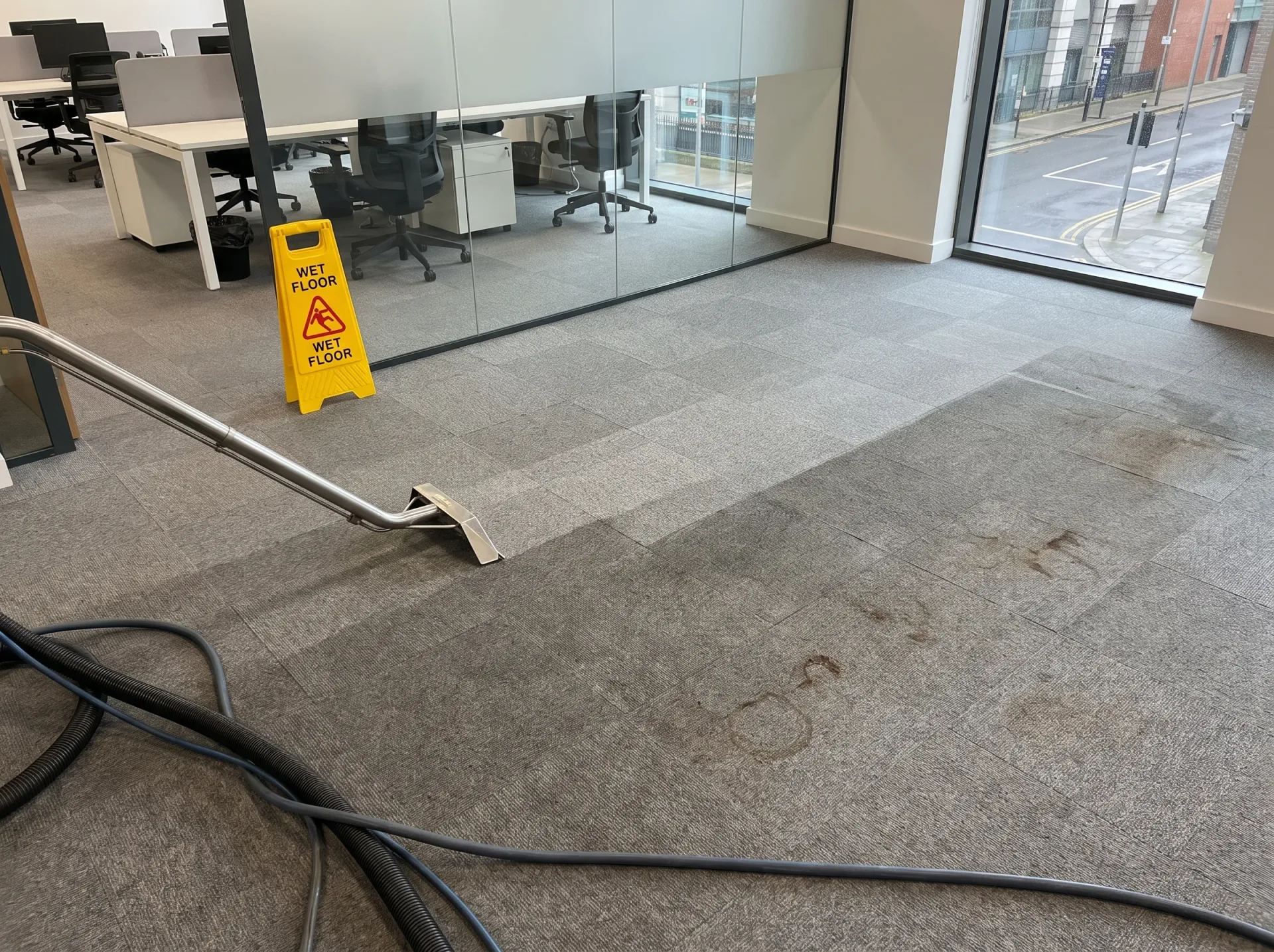 Professional office carpet cleaning with hot water extraction equipment and wet floor warning sign