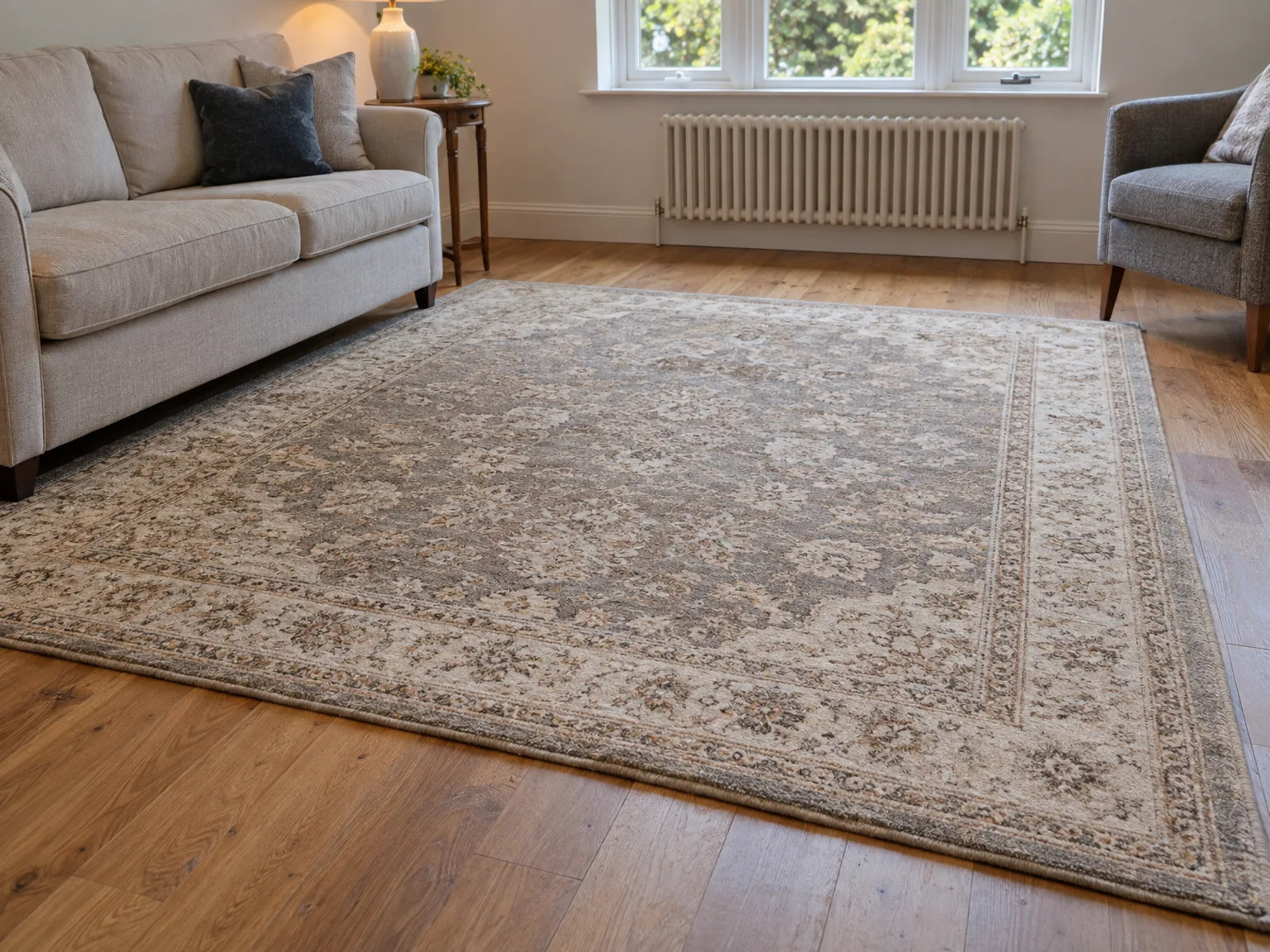 Professionally cleaned oriental rug displayed in bright living room with plush grey sofas and wooden flooring